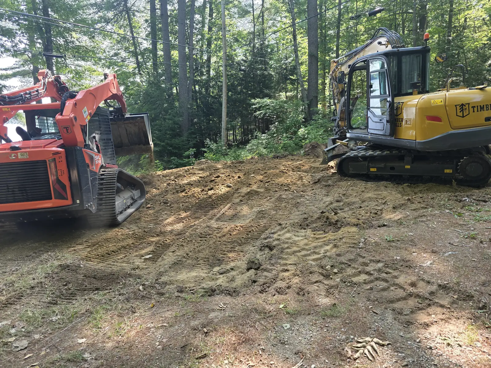Timber Falls excavator and compact loader on a wooded excavation site